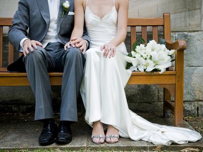 Bride and groom sitting on bench.