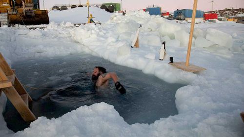 Onderzoekers van het Casey Research Station op Antarctica markeren de winterzonnewende met een duik.