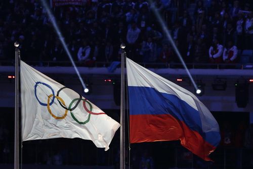 FILE - The Russian national flag, right, flies after it is hoisted next to the Olympic flag during the closing ceremony of the 2014 Winter Olympics in Sochi, Russia, Feb. 23, 2014. (AP Photo/Matthias Schrader, File)