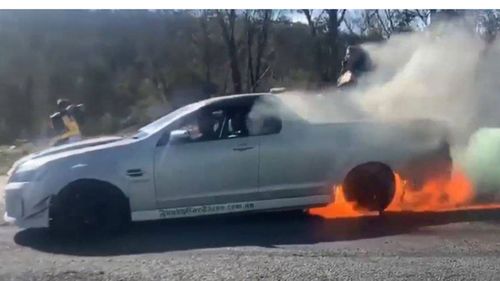 The vehicle's rear tyres erupt into flames as.