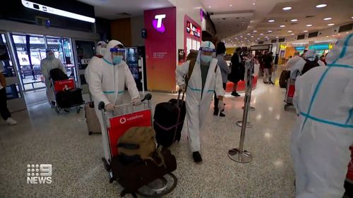 Return travellers arrive in Sydney in hazmat suits.