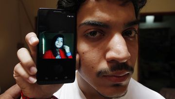 Hasan Khan holds up his phone with a photo of his wife Zeenat Bibi on it. (AFP)