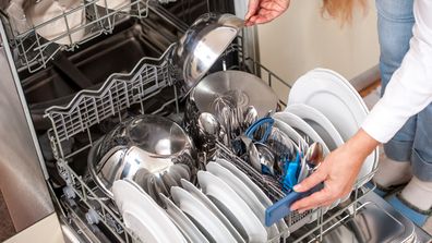 Unloading Dishwasher In The Kitchen