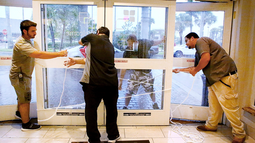 Hilton employees Louie Fonseca, Frankie Monica, Bryan Kinbacher and Jaime Miranda use rope to secure the front door at the Hilton Garden Inn in Fort Myers, Florida.
