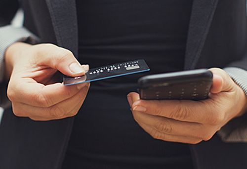 Woman holding bank card and phone (Getty)