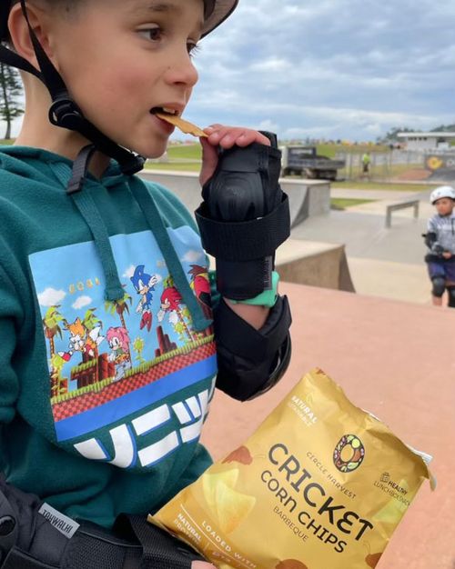 A boy eats Skye Blackburn's cricket corn chips, which are sold in 1000 school canteens across Australia.