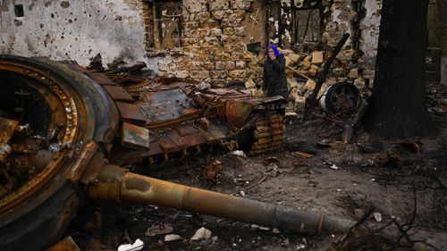 Valentyna Sherba, 68, stands next to a Russian tank in the backyard of her father's home, both destroyed, in the aftermath of a battle between Russian and Ukrainian troops on the outskirts of Chernihiv, northern Ukraine