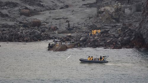 The New Zealand Defence Force recovery team, in yellow suits, enter White Island to recover the bodies.