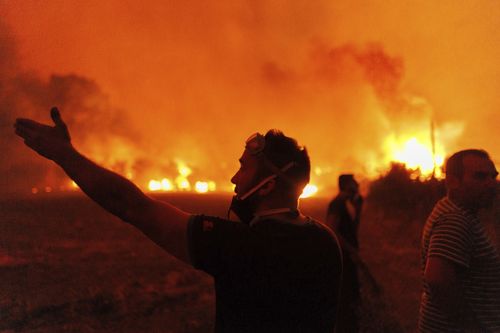 La gente reagisce mentre cerca di spegnere un incendio boschivo nel villaggio di Avantas, vicino alla città di Alessandropoli, nella regione nord-orientale di Evros, in Grecia, lunedì 21 agosto 2023. 