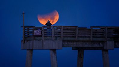 Man taking photo of total lunar eclipse