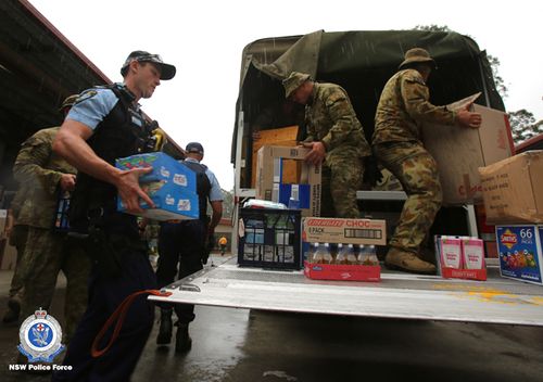 NSW police officers and the ADF unload a truck of supplies.