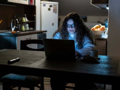 Teenage girl sitting in the dark using the computer