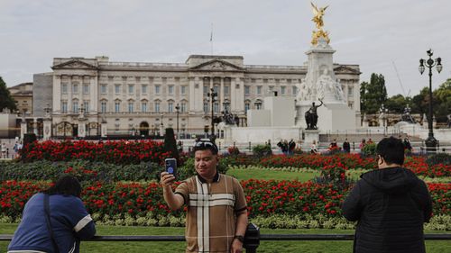Tourists take photographs in front of Buckingham Palace in London.