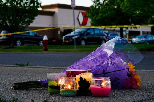 Flowers and candles lay outside the scene of a shooting at a supermarket, in Buffalo, N.Y., Sunday, May 15, 2022.  