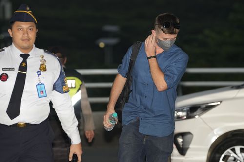 Australian national Bodhi Mani Risby-Jones from Queensland, center, walks with an immigration officer upon arrival at Soekarno-Hatta International Airport in Tangerang, Indonesia, Saturday, June 10, 2023.  