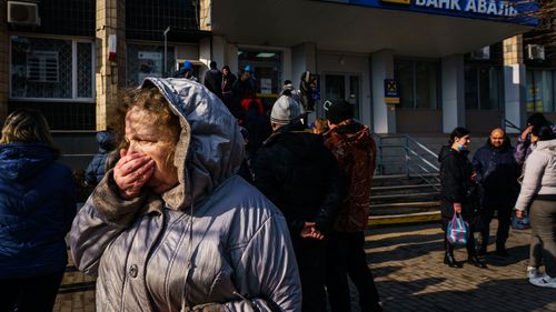 A woman walks away from a line for the ATM that is growing as people try to obtain cash as news of Russia invading Ukraine continues to dominate the headlines, in Slovyansk. 