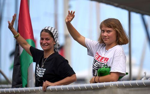 Swedish climate activist Greta Thunberg waves from a boat taking part in a civilian flotilla bound for Gaza, aiming to break the Israeli blockade and deliver humanitarian aid, in Barcelona, Spain, Sunday, Aug. 31, 2025