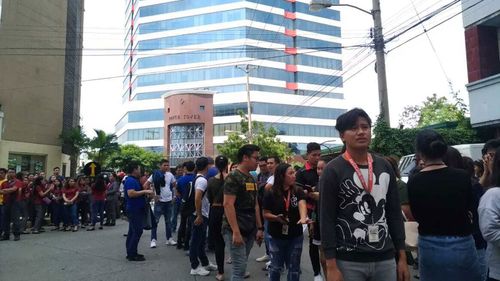 Office employees gather outside of buildings after a powerful earthquake was felt in Davao City, Philippines.