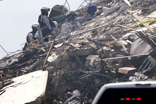 Search and rescue workers go through rubble at a 12-story beachfront condo building which partially collapsed, Friday, June 25, 2021, in the Surfside area of Miami, Florida