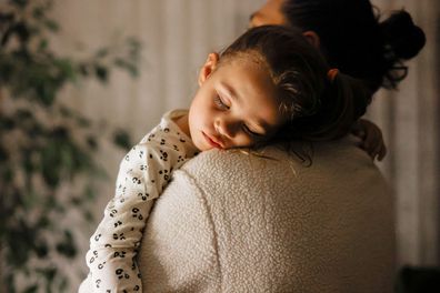 Young girl a sleep on her fathers lap . They are relaxing together on the sofa of their home.