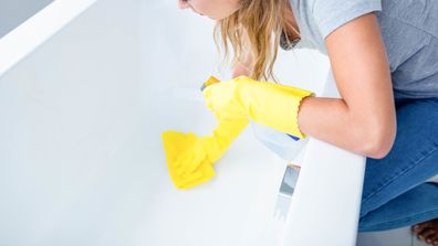 Woman cleaning the bath tub in the bathroom