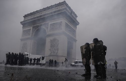 French riot police clear the area around the Arc de Triomphe during violent clashes with Yellow Vest protesters in Paris.