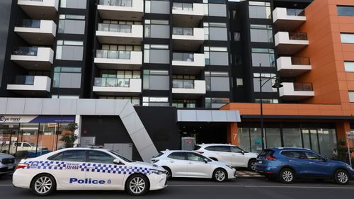 Police drive past the entrance of the Ariel Apartment complex in Melbourne, Australia. 