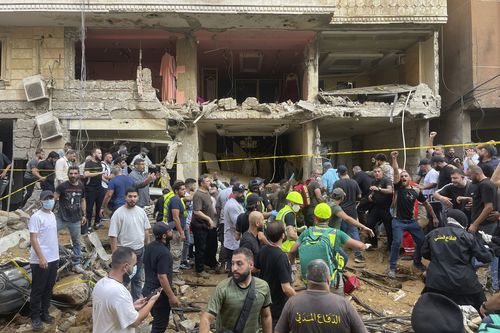 People gather near a damaged building at the scene of an Israeli missile strike in the southern suburbs of Beirut, Friday, Sept. 20, 2024.  