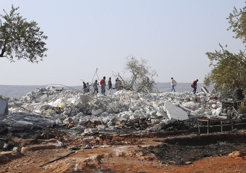 People look at a destroyed house near the village of Barisha, in Idlib province, Syria, after an operation by the US military which targeted and killed Abu Bakr al-Baghdadi, the shadowy leader of the Islamic State group.