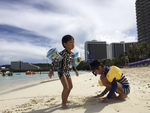 Kids play in the sand in Tumon, Guam. (AAP)