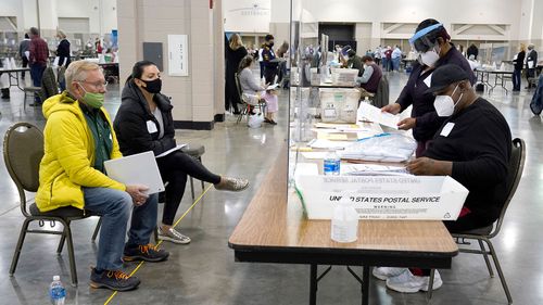 Poll workers verify ballots as recount watchers, left, watch during a manual counting of presidential votes in Milwaukee.