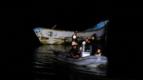 Police officers and rescue workers tow a boat with decomposed bodies found by fishermen, near the Vila do Castelo port in Braganca, Para state, Brazil, on April 14.