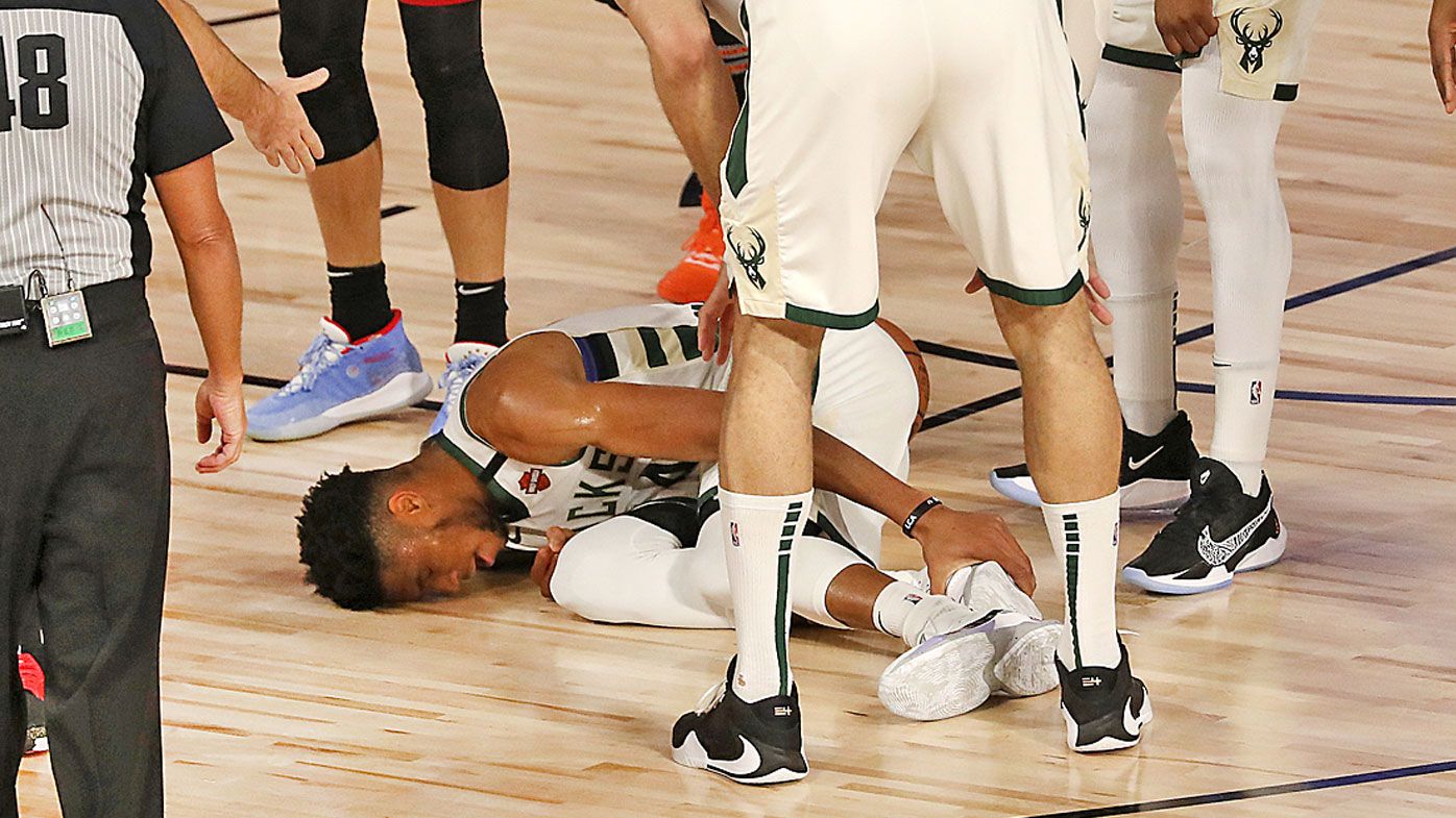 Giannis Antetokounmpo #34 of the Milwaukee Bucks holds his ankle on the court after a foul 