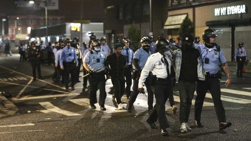 Police lead several people in handcuffs to a police van on 52nd Street in West Philadelphia.