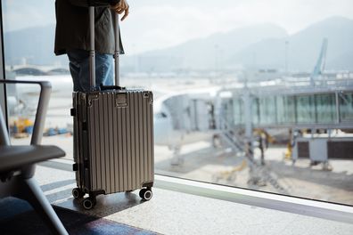 Go on an adventure! Suitcase near window at the airport.