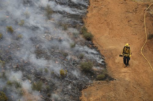 On the edge of destruction, a firefighter surveys damage close up. Picture: EPA