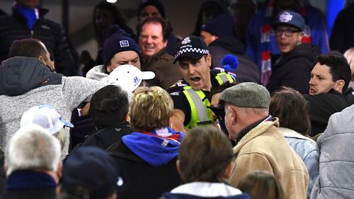 A police officer intervenes in the scuffle.