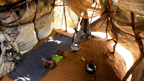 A Somali baby boy sleeps in a makeshift shelter on the outskirts of Dadaab, 2011. Source: AAP