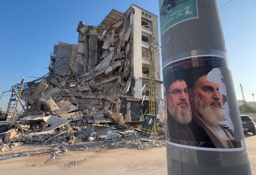 I ritratti del defunto leader di Hezbollah Sayyed Hassan Nasrallah e del defunto fondatore rivoluzionario iraniano Ayatollah Khomeini, sono visti di fronte a un edificio distrutto che ospitava una filiale di Al-Qard Al-Hassan, un istituto finanziario non bancario gestito da Hezbollah, che è stato colpito da un attacco aereo israeliano a Dahiyeh, periferia meridionale di Beirut, Libano, martedì 10 marzo 2026. (AP Photo/Hussein Malla)