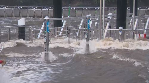 Flood waters rushing past opal gates at Parramatta ferry wharf