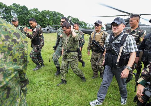 Philippine President Rodrigo Duterte (C), seen carrying a sidearm on his waist, walking to his helicopter after visiting a military camp in Marawi on the southern island of Mindanao. (AFP)