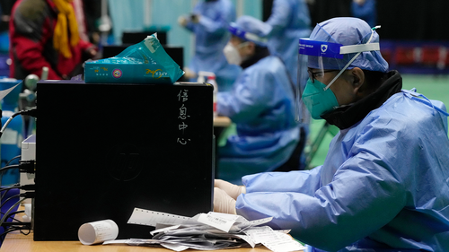 Medical workers attend to visitors at a fever clinic converted from a gymnasium in Beijing, Saturday, Dec. 17, 2022. 