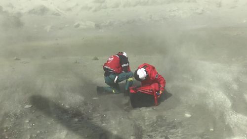 Two of the first responders kneeling among the moon-like dust of White Island following the deadly eruption.