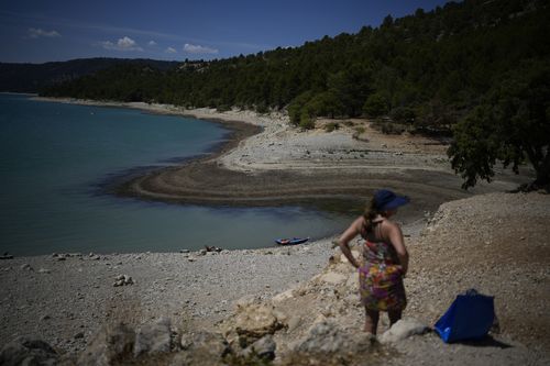 A sunbather stands in front of the receding water line of the Verdon Gorge, southern France, Tuesday, Aug. 9, 2022.