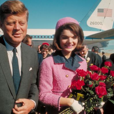 President John F. Kennedy and his wife Jackie, who is holding a bouquet of roses, just after their arrival at the airport for the fateful drive through Dallas.