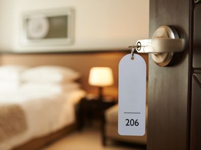 Opened door of hotel room with key in the lock.