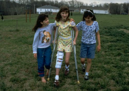 Christine Amer, 13, on crutches walking with help from her sisters after being shot during the shooting attack at Jonesboro Westside Middle School by gunmen Mitchell Johnson, 13, and Drew Golden, 11.
