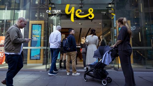 Customers line up outside an Optus shop fron