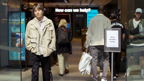 Customers line up outside an Optus shop fron