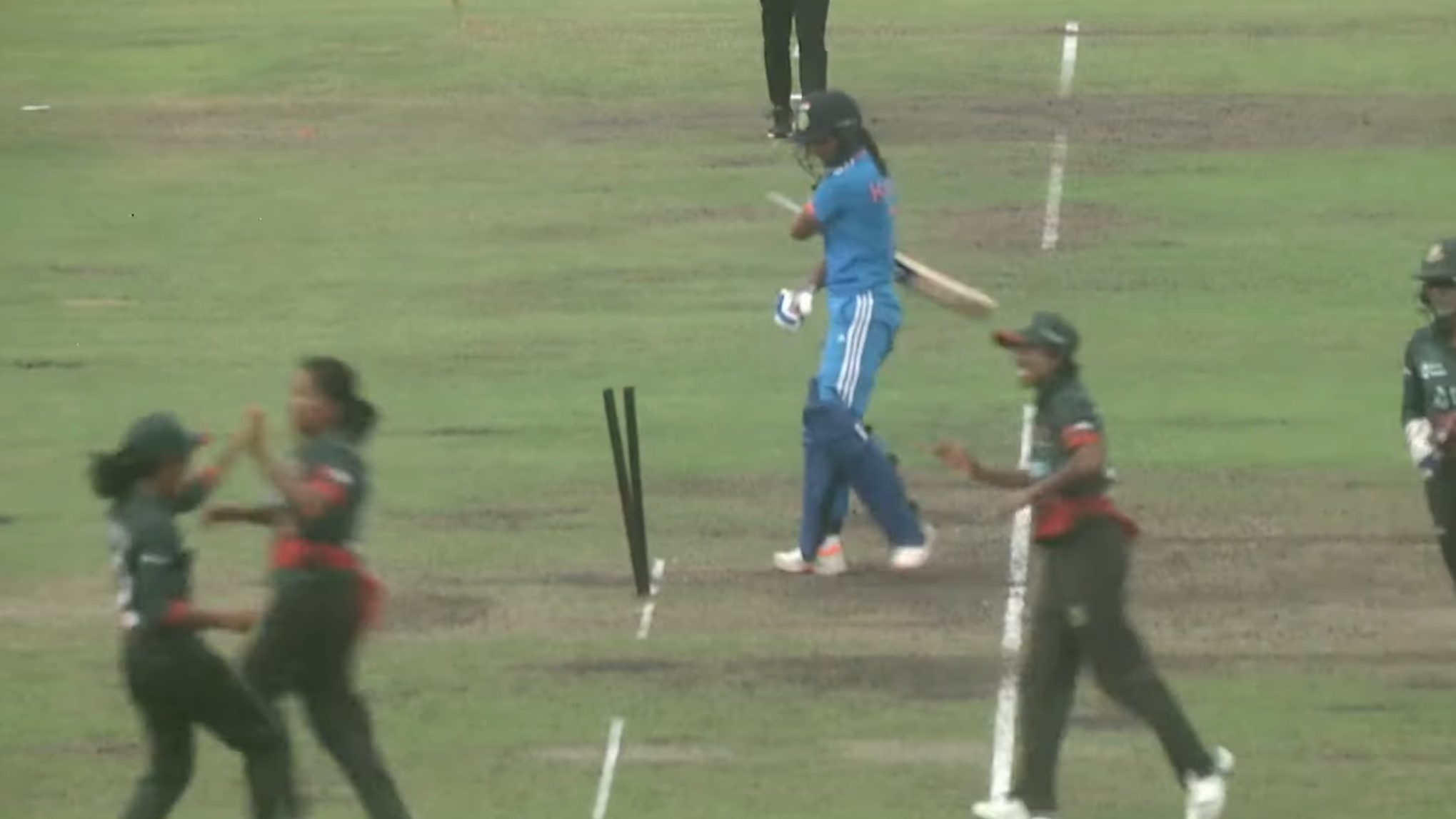 Indian captain Harmanpreet Kaur strikes her stumps as Bangladesh players celebrate her wicket.